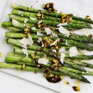 En tallrik med en tillagad hel kyckling omgiven av olika sallader och grönsaker på ett bord.