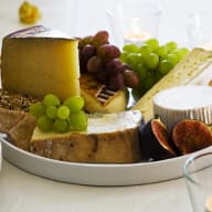 En ostbricka med olika ostar, druvor, fikon och bröd på ett fat.
