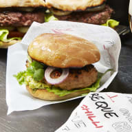 En hamburgare som ligger placerad i en praktisk hamburgerficka av papper.