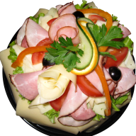 En tallrik med skinka, ost, grönsaker och örter är upplagd som en sallad.