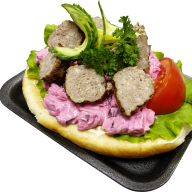 En tallrik innehåller en öppen smörgås med köttbullar, sallad, tomat och dressing.