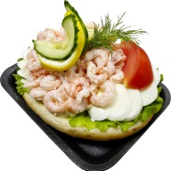 En smörgås med räkor, grönsaker och dill serveras på ett fat.