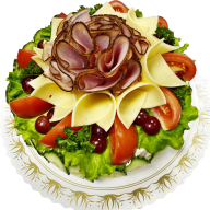 En tallrik med en dekorativ sallad bestående av skinka, ost, grönsaker och frukt.