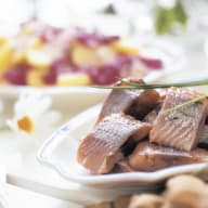 En tallrik med bitar av fisk serveras bredvid en skål med frukt.