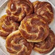 Nygräddade, snurrade kanelbullar passar bra till det extra mörkrostade kaffet. Här upplagda i tre våningar på ett svart fat som bildar kontrast mot de gyllenbruna bullarna.