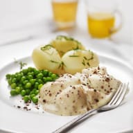 En tallrik med fisk, potatis och ärtor serveras bredvid två glas dryck.