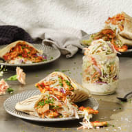 Flera tallrikar med fyllda tortillas står på en yta bredvid en handduk och några gröna växter.