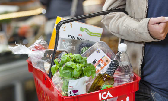 Person i butik med en kundkorg full med mat.