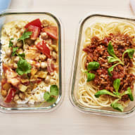 Tre matlådor med olika rätter står bredvid varandra på en yta.