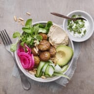 Skål med machesallat, syrad rödlök, falafel, gurka, avokado och hummus. Liten skål med yoghurt bredvid