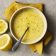 En citrondressing ligger i en skål, runtomkring ligger halva citroner.