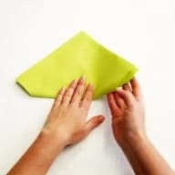 Två händer som viker en grön servett