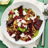 Rödbetor, granatäpple, quinoa och gröna blad upplagd i en skål