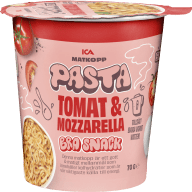 En matkopp med pasta innehållande tomat och mozzarella står på ett bord.