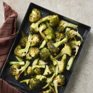 En svart form med broccoli ligger på en ljus yta bredvid en tygservett.