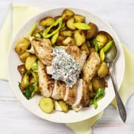 En pytt av färskpotatis, rädisor och purjolök tillsammans med stekt kyckling och östsås. Tallriken står på en gul tygservett.