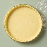 En pajdeg ligger i en rund form med vågiga kanter.