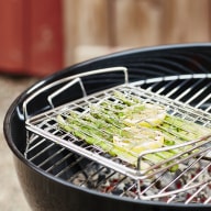 En grill med ett grillgaller där sparris ligger på en grillkorg.