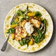 På en gul tallrik ligger en sallad med gulbetor, havreris och stekt halloumi.