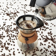 Häller sjudande vatten över kaffepulver i en pour over.