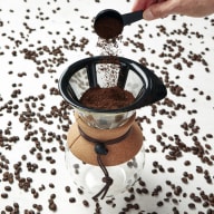 Doserar nymalet kaffepulver i pour over-kanna.