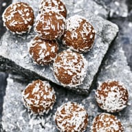 Flera runda bollar med kokosflingor ligger på en stenplatta.