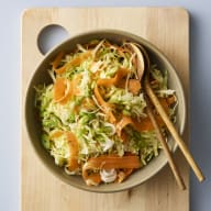 En skål med kålsallad står på en skärbräda.