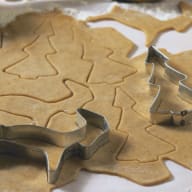 Utkavlad deg med pepparkaksformar och utskurna pepparkaksfigurer.