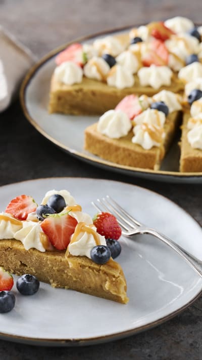 En kolakladdkaka med bär på toppen ligger på en tallrik bredvid en gaffel.