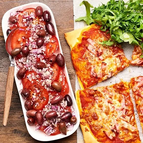 Pizza med rökt skinka, tomatsallad och oliver