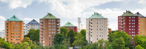 Gröna träd runt flera färgglada höghus som man ser på avstånd.