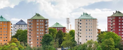 Gröna träd runt flera färgglada höghus som man ser på avstånd.