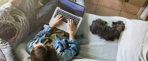 Kille och tjej i soffa med laptop intill flyttkartonger