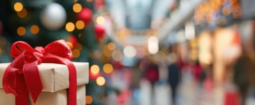 Julklapp med en julgran i bakgrunden i ett shoppingcentrum.