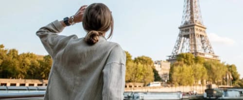 Kvinna som fotar Eiffeltornet med sin mobiltelefon.