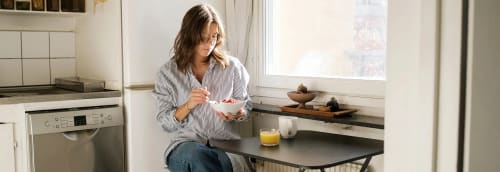 Tjej äter frukost i sitt lilla kök