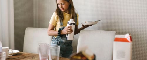 Barn som dukar av frukostbordet