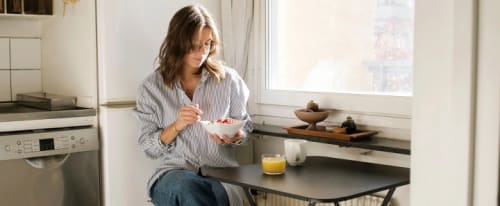 Tjej äter frukost i sitt lilla kök