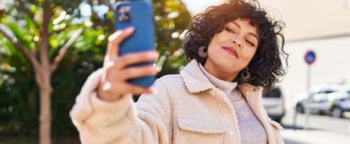 Ung kvinna ler mot sin smartphone och tar en selfie