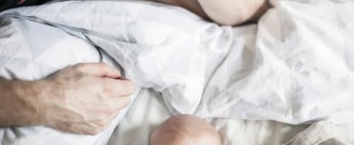 Pappa ligger på sängen och tittar på sin baby 
