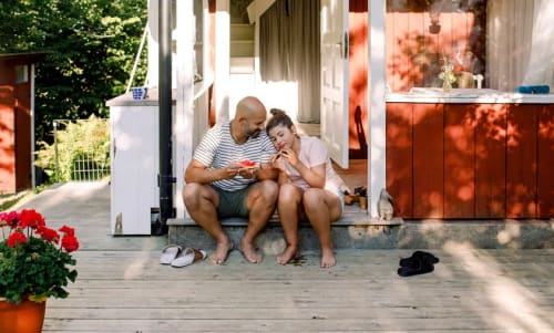 En pappa och dotter sitter på trappsteget till farstun till en sommarstuga.