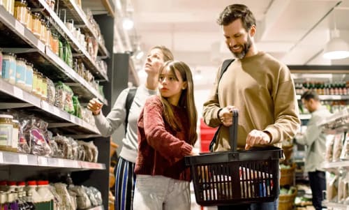 En familj med en mamma, pappa och en dotter som handlar mat i en mataffär.