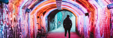 Man går i tunnel med graffitimålningar