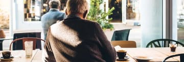 Senior som sitter och fikar på ett café