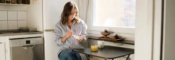 Tjej äter frukost i sitt lilla kök