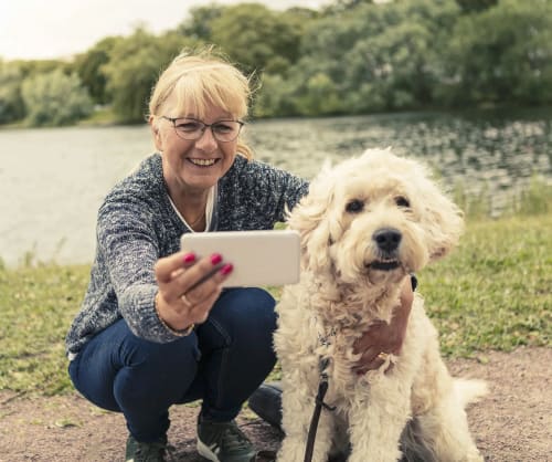 Kvinna tar en selfie med sin hund. I vår pensionsguide kan du ser hur du borde spara.