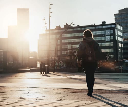 Tjej går över ett torg i motljus.