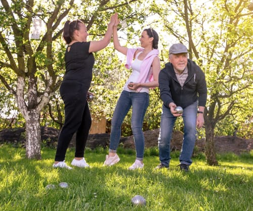 Familj som spelar boule i trädgården. Pensionspara för en trygg pension hos ICA Banken.