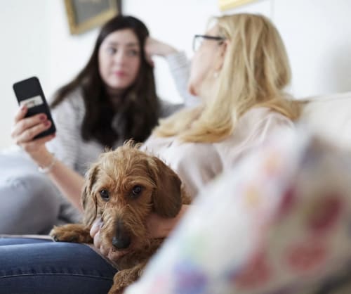 Mamma, dotter och hund i en soffa. Pensionsspara hos ICA Banken för tryggar pension.