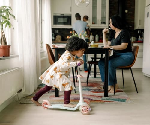 Familj som gör olika saker i ett kök. Med vår bolåneguide får du råd kring att låna till bostad.